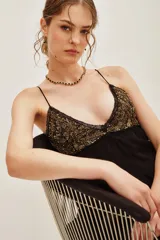 Top de tirantes finos color negro, con escote en V decorado con bordados de lentejuelas y canutillos dorados. Presenta detalles de encaje en los bordes del escote.