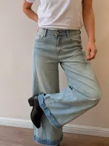 Pantalón jeans tipo palazzo de corte amplio y tiro medio-alto, con lavado celeste vintage y dobladillo vuelto con detalle de rayas en la terminación. Cuenta con bolsillos delanteros y traseros.