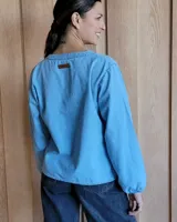 Blusa celeste de manga larga con escote en V y detalle bordado en el cuello.