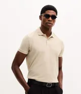 Camisa polo de corte regular, color beige, con textura en el tejido, cuello plegado con botones y manga corta.