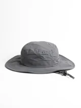 Gorro tipo bucket de tela técnica color gris oscuro, con ala ancha y cordón ajustable para el mentón. Presenta un pequeño logo bordado en el frente que simula una montaña.