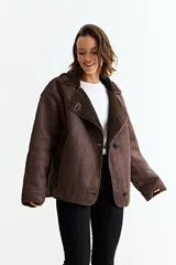 Chaqueta de estilo aviador en color marrón, confeccionada en material simil gamuza con interior y solapas de corderito sintético. Presenta cierre frontal con botones, corte holgado y mangas largas.