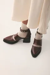 Zapato de cuero color marrón con textura de reptil, con punta fina, corte lateral y pulsera con hebilla y apliques metálicos.