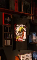 Remera de manga corta con cuello redondo y calce oversize, color negro con efecto nevado. Presenta un estampado gráfico frontal con el logo de la banda The Prodigy y elementos artísticos.