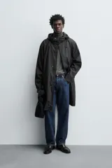 Parka de tejido con acabado engomado, diseño de corte recto y largo medio. Presenta cuello subido con capucha ajustable, cierre frontal con cremallera oculta bajo solapa con botones a presión, mangas largas y bolsillos laterales de vivo.