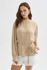 Blusa de poliéster color negro con cuello alto, mangas largas, diseño holgado, detalles de frunces y lazo ajustable en la cintura.