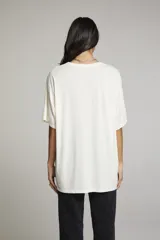 Remera color crema de corte holgado con estampado de la palabra "TEXAS" en color naranja.