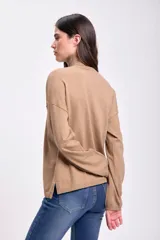 Polera de tejido de punto fino en color beige, con cuello alto, mangas largas y corte holgado.