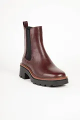 Bota marrón de cuero sintético, estilo Chelsea, con punta redonda, pieza elastizada en los laterales y suela tipo tractor de 6cm de alto.