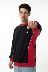 Buzo de corte oversize con diseño colorblock en negro y rojo. Presenta cuello redondo, puños y cintura acanalados, y paneles laterales con vivos blancos. Incluye logo bordado en el pecho.