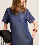 Vestido corto de color azul claro, confeccionado en liocel, con cuello redondo, mangas cortas y detalle de costura horizontal en el busto. Cuenta con bolsillos laterales.