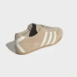 Championes Adidas modelo Tokyo de corte bajo y diseño retro. Confeccionados en gamuza color beige con las icónicas tres tiras laterales en color crema y suela de caucho natural.