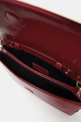 Bolso tipo bandolera de diseño estructurado, acabado brillante en color rojo y correa de cadena dorada. Cuenta con solapa frontal y doble compartimento interior.