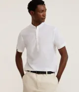 Camisa de lino y algodón color blanco, con cuello mao, cierre frontal parcial con botones y mangas cortas.