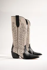 Botas texanas de cuero color beige con detalles bordados en negro y caña alta.