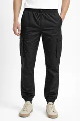 Pantalón cargo de nylon color negro, con cintura elástica ajustable, bolsillos laterales con solapa y puños elásticos en los tobillos. Presenta un logo de goma aplicado en uno de los bolsillos laterales.