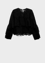 Blusa negra de manga larga con diseño de volantes y bordados perforados. Presenta cuello redondo con cierre de lazo y corte recto.
