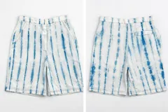 Bermuda de algodón y lino, color blanco con teñido artesanal en índigo que genera un patrón de rayas verticales suaves. Presenta cierre con botones y gancho oculto, y bolsillos laterales.