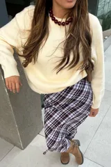 Buzo de punto color crudo, con cuello redondo y mangas largas, de diseño holgado y acabado clásico.