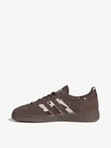 Championes Adidas Handball Spezial, color marrón con detalles de textura animal print en las icónicas tres tiras y en el talón. Presenta el nombre del modelo estampado en dorado en el lateral y suela de goma semitransparente.