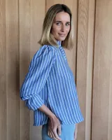 Blusa de algodón con cuello mao y volados, mangas largas con puños elásticos y corte holgado.