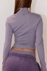 Campera deportiva de corte ajustado confeccionada en tejido funcional con tecnología SoftMove y DryMove. Presenta cuello elevado, cierre frontal con protección para el mentón y mangas largas con abertura para el pulgar.