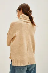 Polera de cuello alto en color beige, confeccionada en tejido de punto suave. Presenta un diseño clásico de manga larga con puños acanalados.