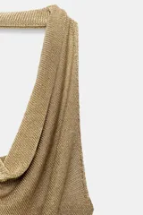 Top de punto con hilo metalizado color dorado, de cuello halter con escote fluido y espalda descubierta.