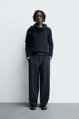 Pantalón de corte balloon fit, color negro, con bolsillos laterales de vivo y bolsillos traseros con solapa. Presenta cierre frontal con cremallera y botón.