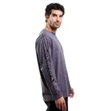 Remera de manga larga Volcom, color gris, con cuello redondo y puños acanalados. Presenta un pequeño logo circular estampado en el pecho y el nombre de la marca estampado verticalmente a lo largo de la manga derecha.