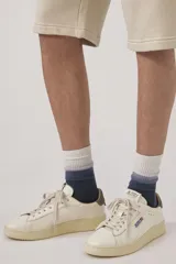 Zapatillas urbanas Autry modelo Dallas Low, color blanco hueso con detalles en marrón en el talón y logo de la marca en el lateral.