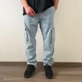 Pantalón cargo de jean azul, de corte recto y tiro medio, con bolsillos laterales con solapa en las piernas.