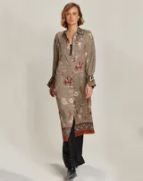 Camisa tipo túnica midi de viscosa, con estampado western que incluye motivos de caballos, cactus y calaveras. Presenta cuello clásico, cierre frontal abotonado, mangas largas con puños anchos en contraste y un diseño con guardas decorativas en el ruedo.