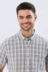 Camisa de manga corta confeccionada en mezcla de lino y algodón, con diseño a cuadros en tonos gris, blanco y azul. Presenta cuello camisero con botones y bolsillo ojal en el pecho con detalle bordado.
