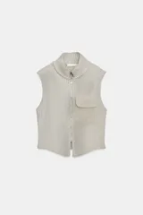 Top chaleco de punto acanalado con efecto lavado, cuello subido, cierre frontal con cremallera y bolsillo de plastrón en el delantero. Presenta un diseño sin mangas con bajo asimétrico.