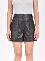 Short negro de cuero sintético, tiro alto, con bolsillos delanteros y cierre frontal con botón.