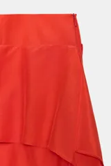 Falda midi de tiro medio en color rojo, confeccionada en tejido con viscosa. Presenta un diseño de capas horizontales con volantes laterales y cierre de cremallera oculta en la costura.