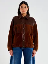 Chaqueta de cuero marrón con diseño western, combinando cuero liso en la parte superior (cuello y tapeta frontal) y gamuza en el cuerpo y mangas. Presenta flecos decorativos en el pecho.