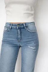 Pantalón de jean corte regular fit en color celeste claro. Presenta un diseño con pequeñas roturas frontales y botamanga con doblez, confeccionado en denim con elastano para mayor flexibilidad y comodidad.