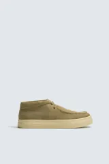 Zapato de cordones estilo wallabee, confeccionado en piel con acabado de serraje en color tostado. Presenta detalle de costura tipo bordón en el empeine, horma redonda y suela de goma a contraste.