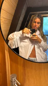 Camisa blanca de mangas largas con flecos en la espalda y en las mangas.