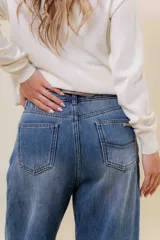 Jean de corte wide leg y tiro alto, confeccionado en denim rígido con un ligero efecto de desgaste. Presenta un diseño de calce relajado con pernera amplia, cintura marcada, bolsillos clásicos y cierre frontal con botón metálico.