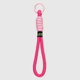 Colgante para bolso tipo strap de cuerda trenzada en color fucsia, con detalle de nudo en tono rosa claro y mosquetón circular a tono. Incluye etiqueta textil negra con el logo de la marca en verde.