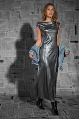 Vestido largo plateado de fiesta, confeccionado en tejido fluido con sutiles destellos. Presenta escote barco y espalda descubierta.