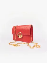 Cartera bandolera de cuero color rojo con motivo piel de avestruz, cadena dorada y cierre con botón a presión metálico dorado.