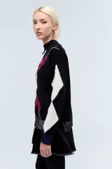Sweater de punto negro con cuello alto y diseño de jacquard con rombos blancos y bordado de flores fucsia.