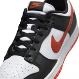 Championes Nike Dunk Low Retro con diseño tricolor en blanco, negro y naranja. Presentan una base de cuero blanco con superposiciones en cuero negro, el icónico swoosh lateral en color naranja y suela de goma naranja.