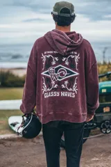 Hoodie de corte boxy fit en color bordó con efecto lavado. Presenta una estampa gráfica en la espalda con motivos playeros, palmeras y el texto 'Classy Waves'.