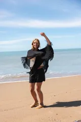 Capa tejida color negro, con flecos largos en los bordes.