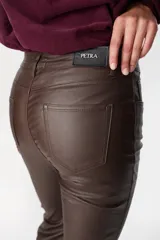 Pantalón de ecocuero color marrón, de corte recto con terminación ligeramente acampanada y tajos frontales en el ruedo. Cuenta con cierre y botón frontal, además de bolsillos laterales y traseros.